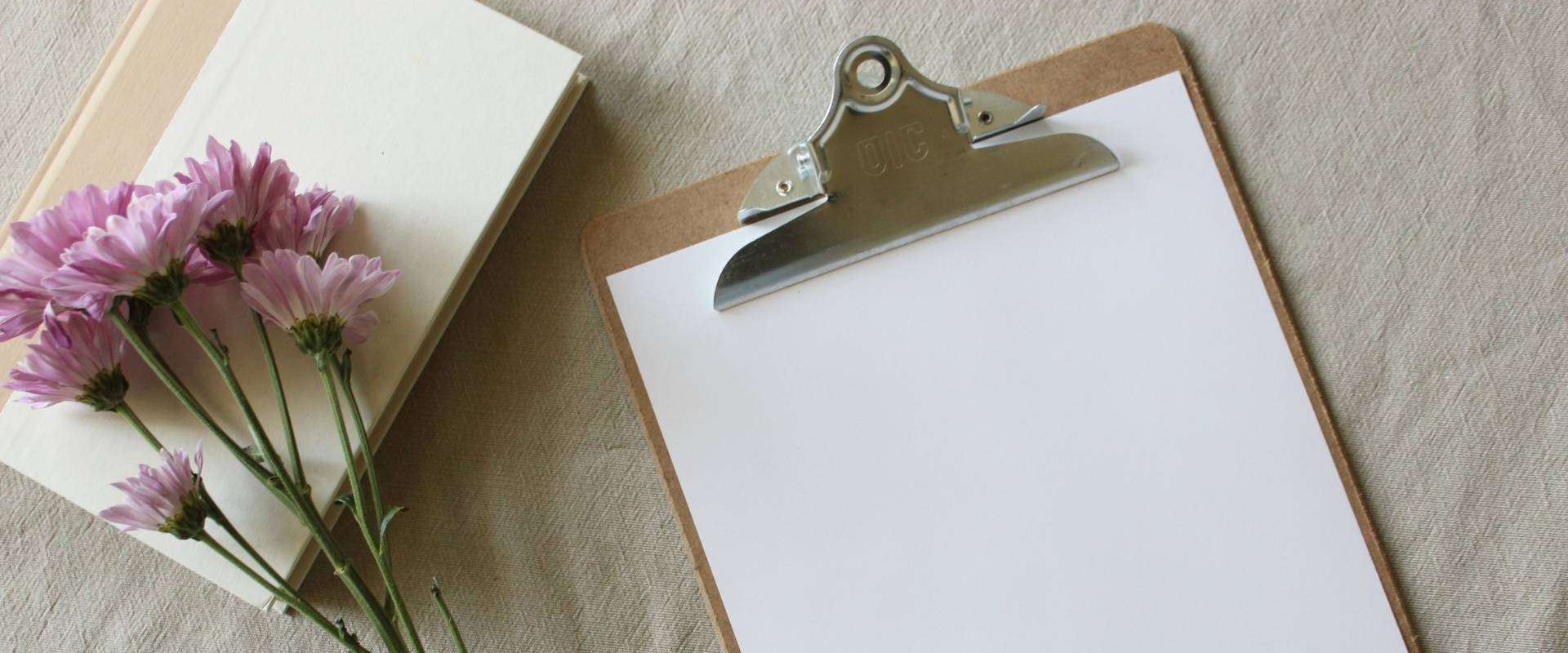 Funeral planning checklist on a clipboard with sympathy flowers