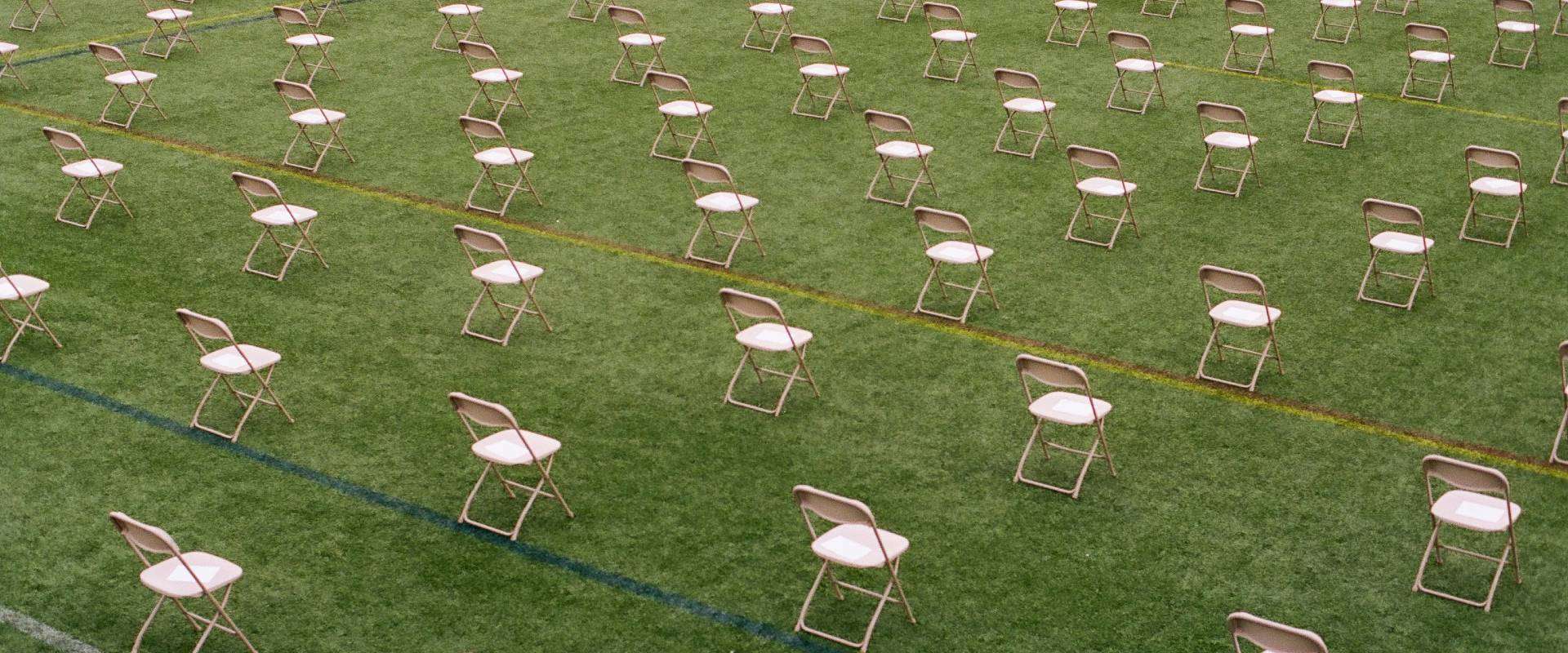 Empty rows of folding chairs on a grassy lawn, symbolizing how COVID changed funerals with social distancing and outdoor services.