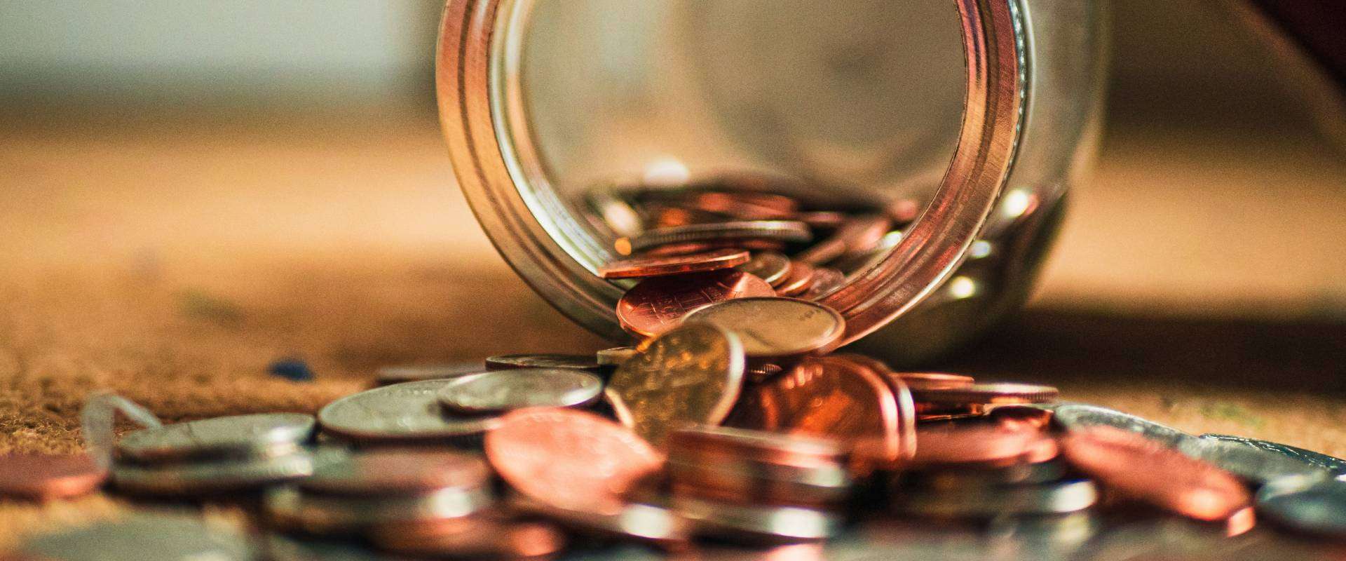 A tipped-over jar with loose change symbolizing saving money for funeral expenses
